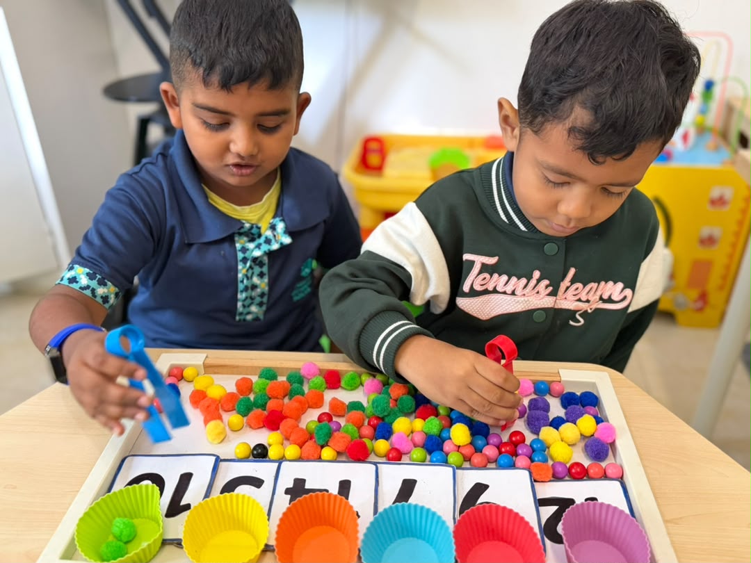 Two Early Years boys sorting pom-poms into coloured cups