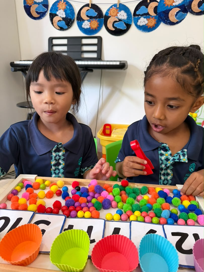 Two Early Years girls working together on the pom-pom sorting tray