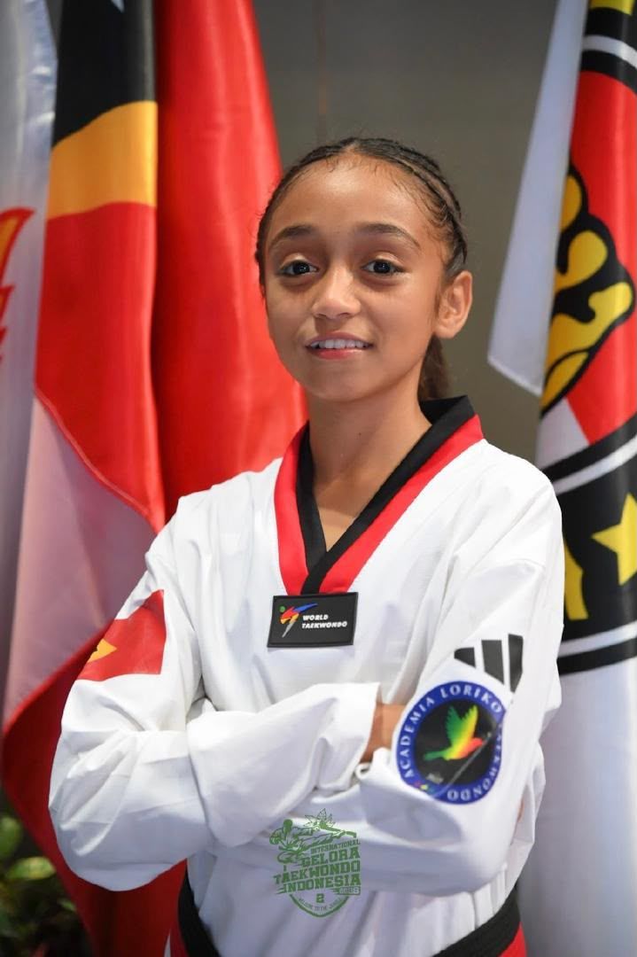 Neymia wearing her taekwondo uniform in front of flags