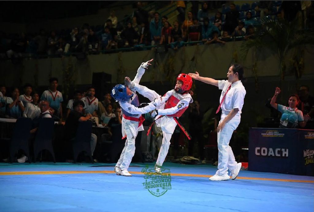 Two cadet athletes competing in a kyorugi bout while a referee watches