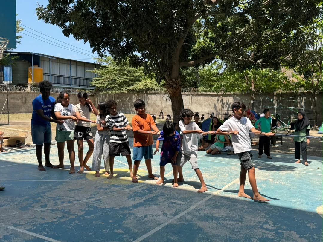Students pulling together in a tug of war on the school court