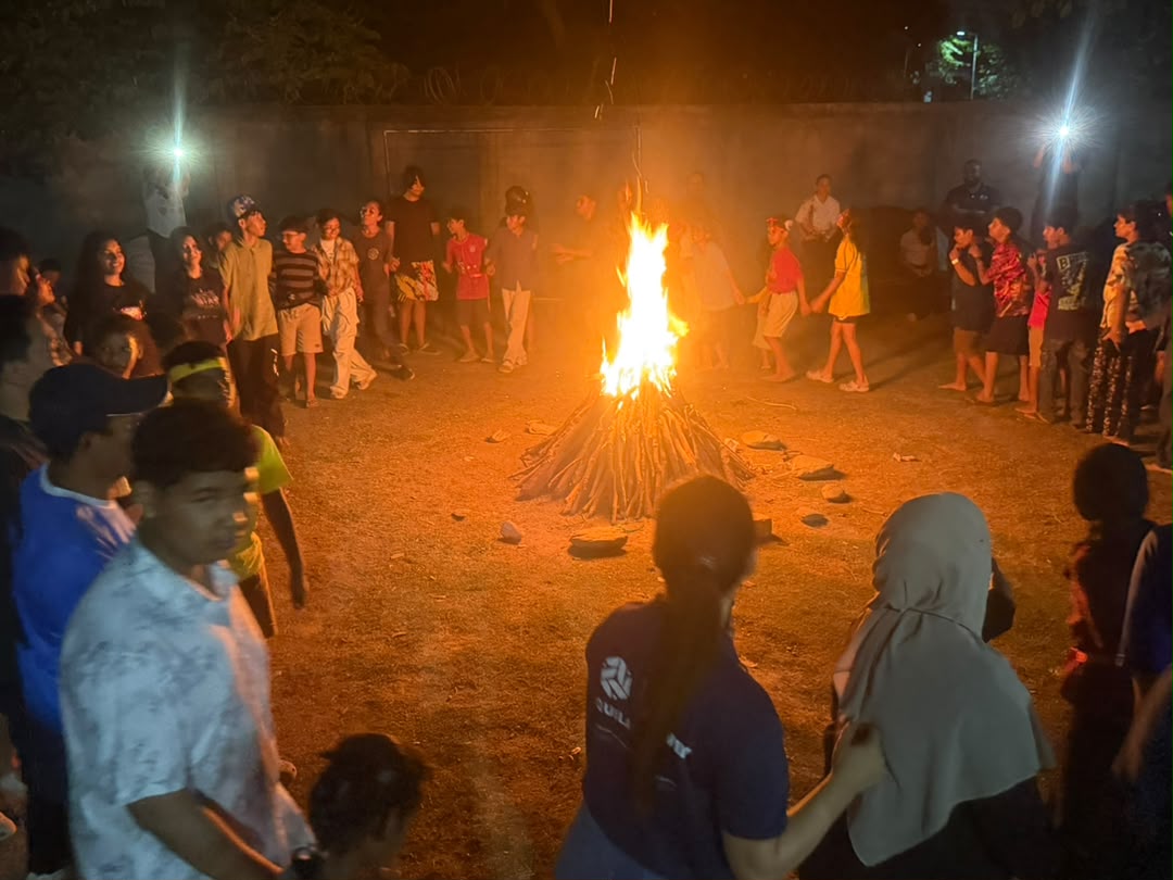 Students gathered around a campfire at night