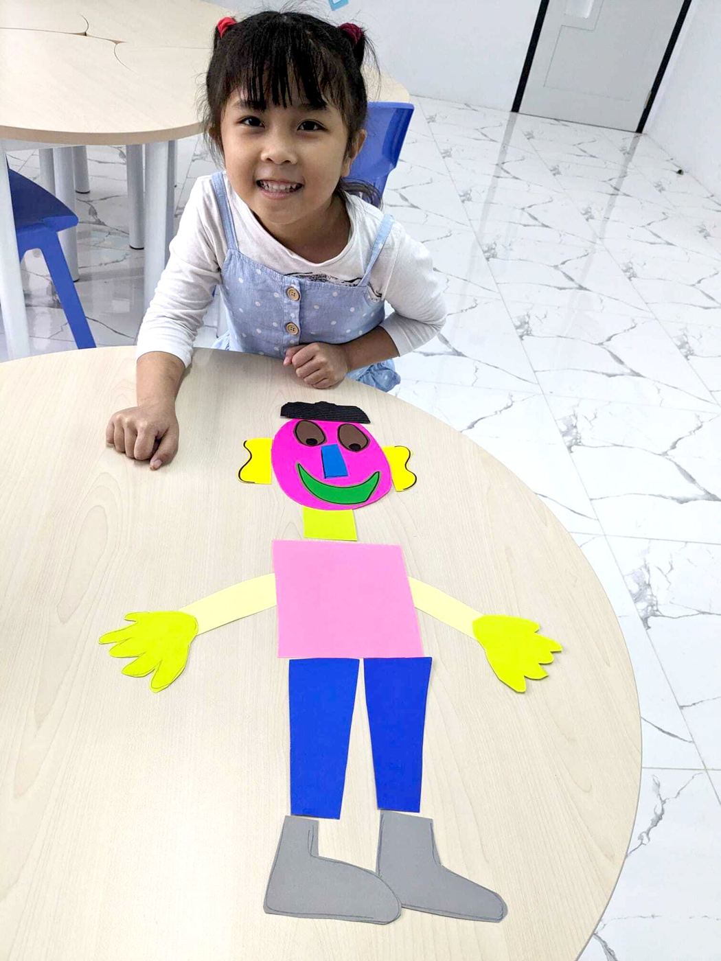 A pupil smiling beside her paper-craft figure